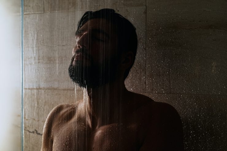 Uomo sotto l'acqua della doccia